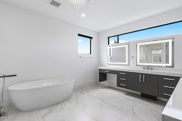 full bath featuring a freestanding tub, vanity, marble finish floor, baseboards, and visible vents