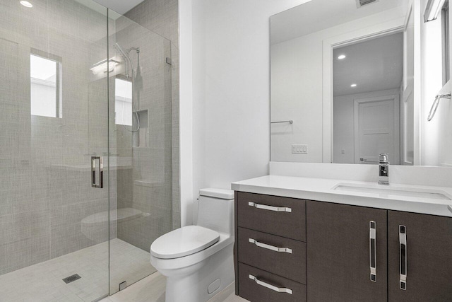 bathroom featuring vanity, a shower with shower door, and toilet