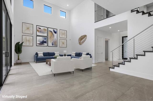 living area with baseboards, a high ceiling, recessed lighting, and stairs