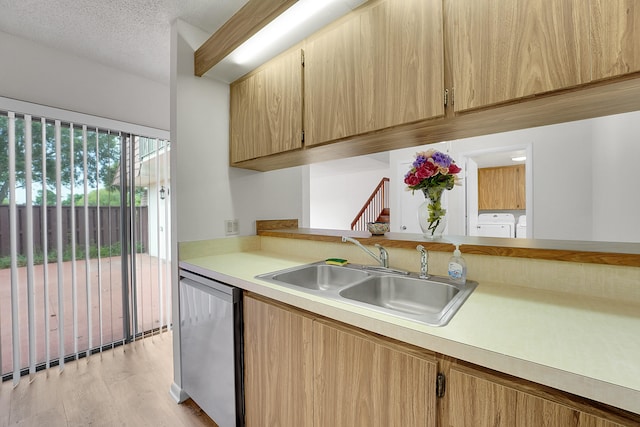 kitchen with dishwasher, separate washer and dryer, sink, light wood-type flooring, and a textured ceiling