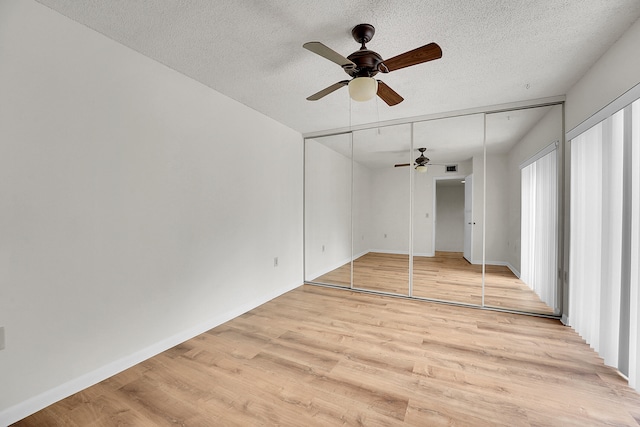 unfurnished bedroom with ceiling fan, light wood-type flooring, a closet, and a textured ceiling