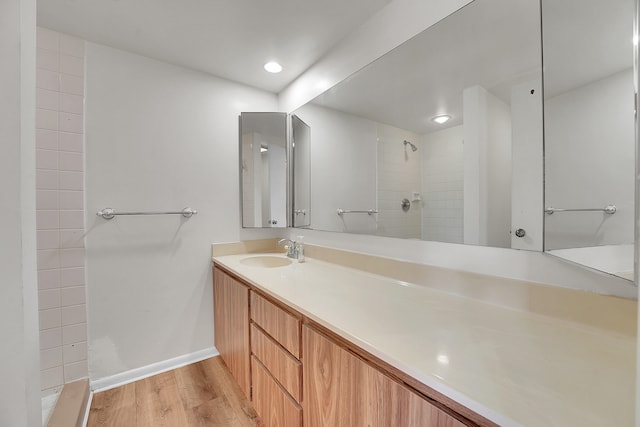 bathroom featuring tiled shower, wood-type flooring, and vanity