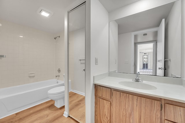 full bathroom with wood-type flooring, toilet, tiled shower / bath, and vanity