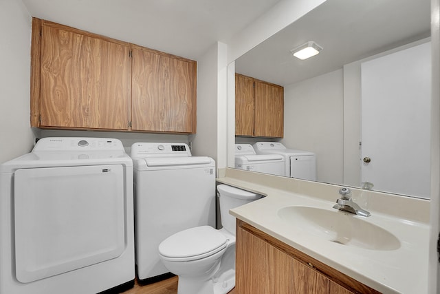 bathroom with toilet, hardwood / wood-style flooring, washer and clothes dryer, and vanity