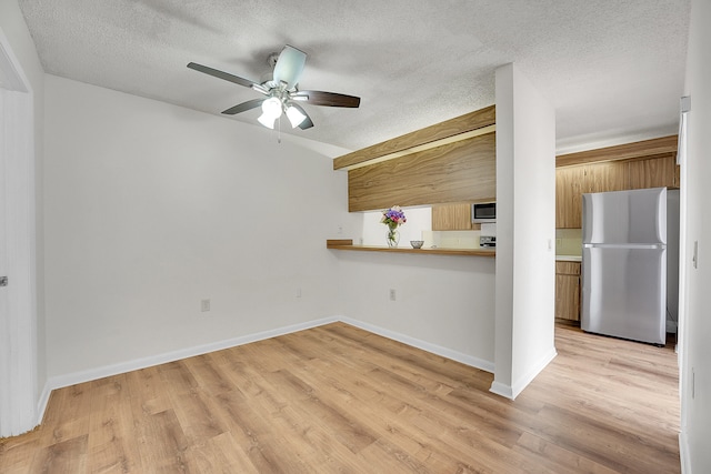 kitchen with ceiling fan, appliances with stainless steel finishes, light wood-type flooring, and a textured ceiling