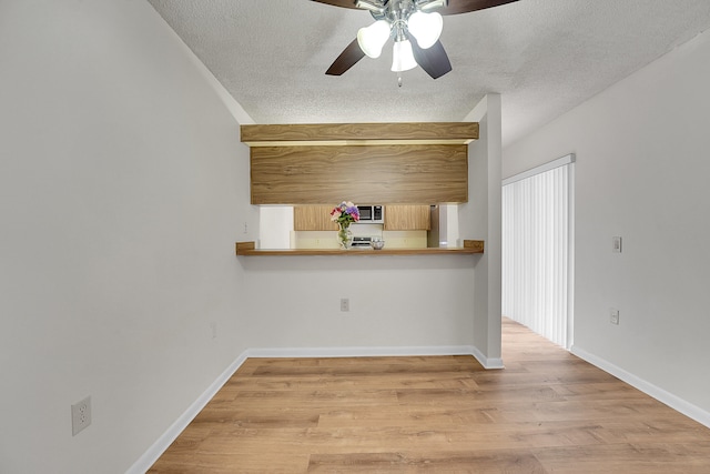 kitchen with ceiling fan, light wood-type flooring, and a textured ceiling