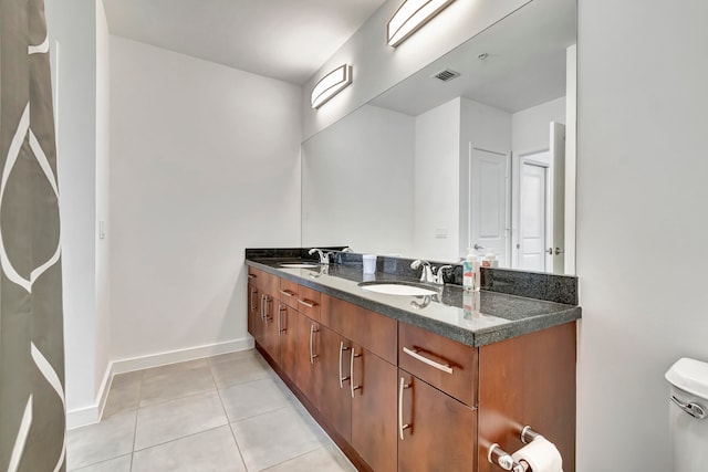 bathroom featuring dual vanity, toilet, and tile patterned floors