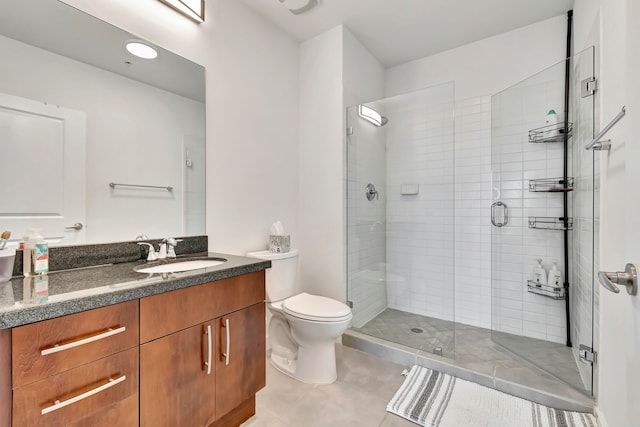 bathroom with a shower with door, toilet, vanity, and tile patterned floors