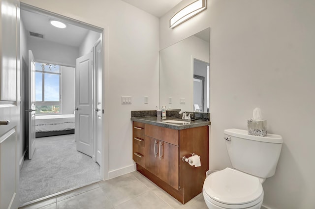 ensuite bathroom featuring tile patterned flooring, visible vents, baseboards, toilet, and vanity