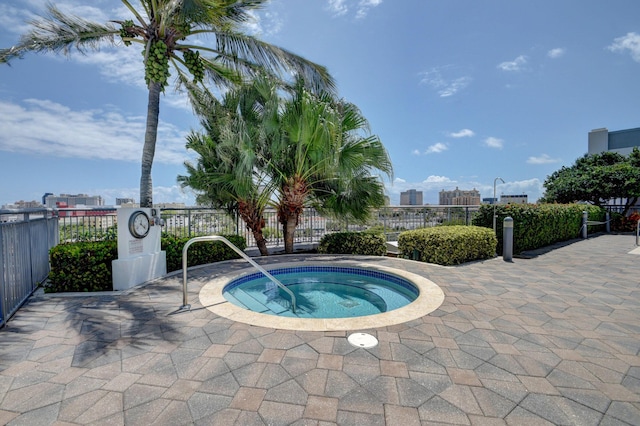 view of swimming pool with a city view, a hot tub, and fence