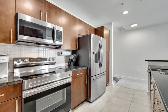 kitchen featuring light tile patterned floors, visible vents, stainless steel appliances, tasteful backsplash, and brown cabinets