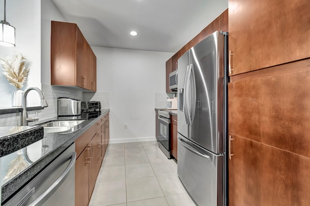 kitchen featuring stainless steel appliances, tasteful backsplash, sink, light tile patterned flooring, and dark stone countertops