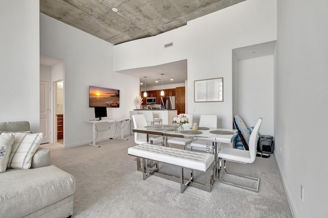 dining area featuring visible vents, light colored carpet, baseboards, and a towering ceiling