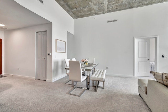 dining room featuring a high ceiling and light carpet