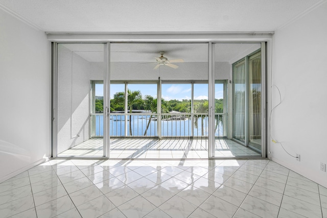 empty room with a water view, ceiling fan, ornamental molding, and a textured ceiling