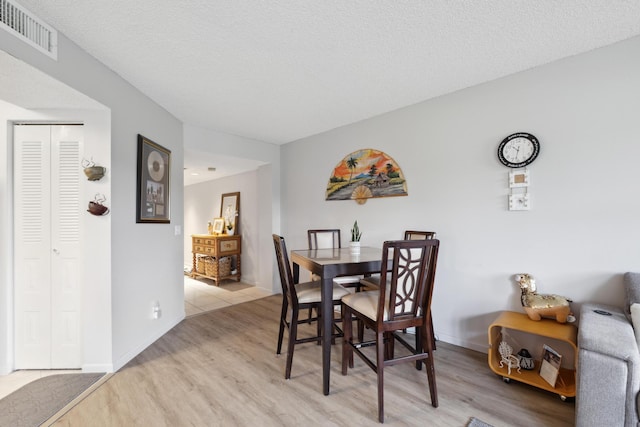 dining area with a textured ceiling and light wood-type flooring