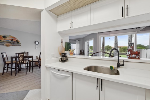 kitchen featuring white cabinetry, sink, white dishwasher, and light hardwood / wood-style flooring