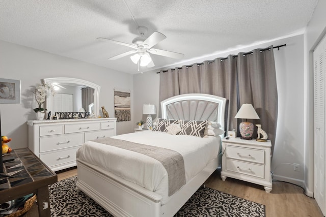 bedroom with ceiling fan, hardwood / wood-style flooring, and a textured ceiling