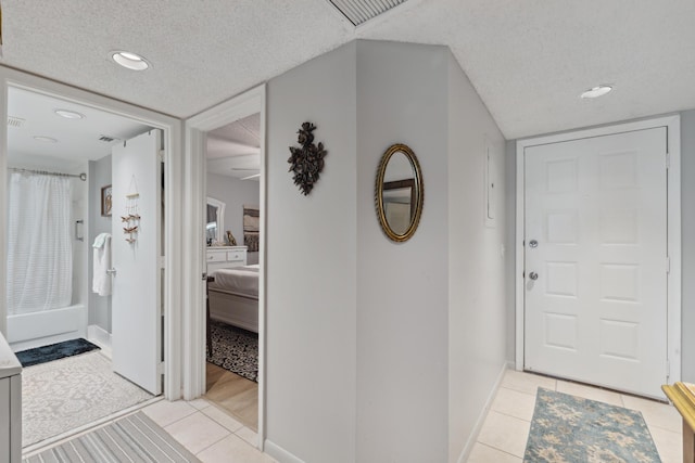 entryway with light tile patterned flooring and a textured ceiling