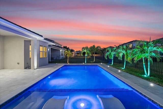 pool at dusk with a patio area