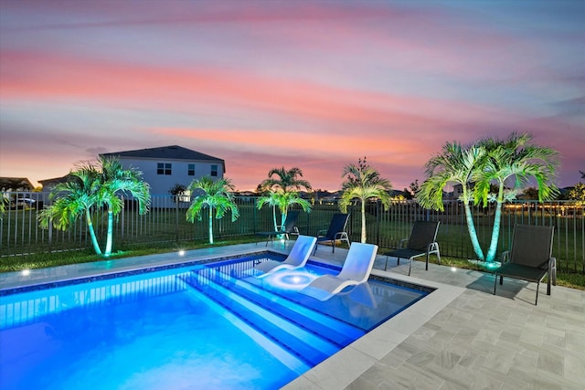 pool at dusk featuring a patio