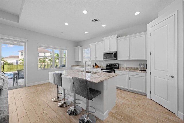 kitchen with a kitchen island with sink, sink, stainless steel appliances, and white cabinetry