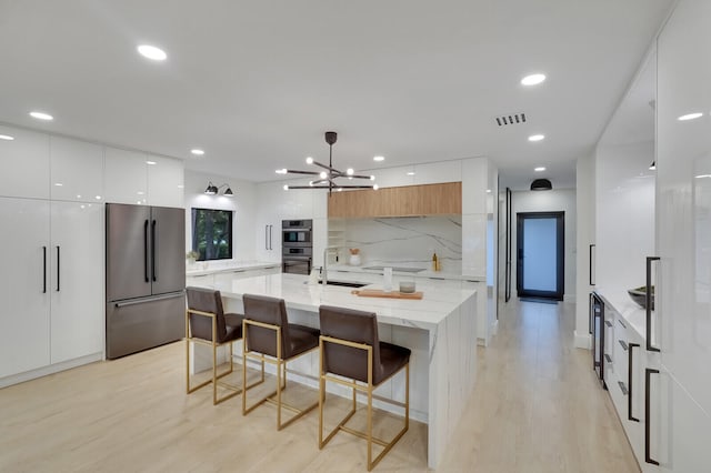 kitchen with light wood-type flooring, white cabinetry, stainless steel appliances, and decorative backsplash