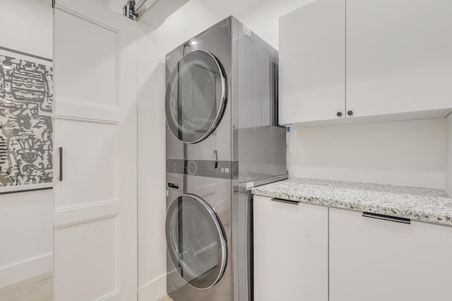 laundry room with cabinets and stacked washer / dryer