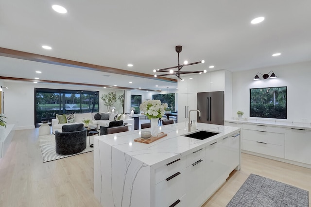 kitchen with light hardwood / wood-style floors, sink, high quality fridge, a spacious island, and pendant lighting