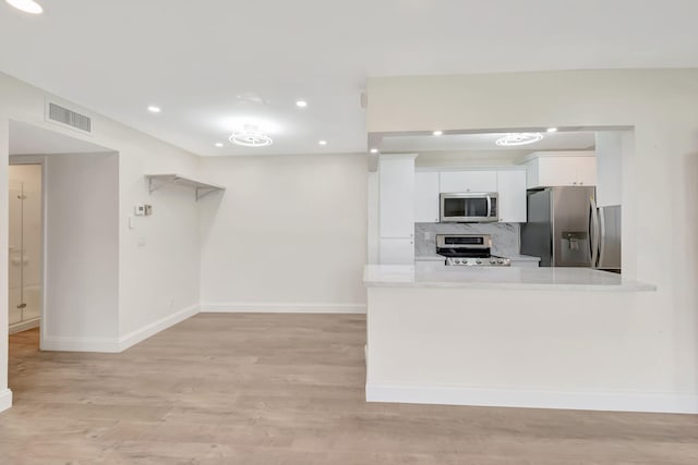 kitchen with backsplash, light hardwood / wood-style floors, white cabinetry, stainless steel appliances, and kitchen peninsula