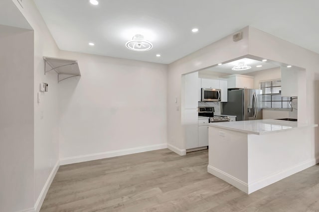 kitchen with white cabinets, kitchen peninsula, light hardwood / wood-style flooring, and stainless steel appliances