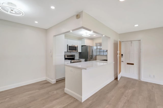 kitchen with kitchen peninsula, light hardwood / wood-style flooring, white cabinetry, and stainless steel appliances