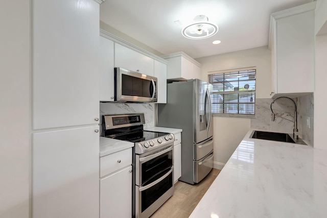 kitchen with light hardwood / wood-style flooring, backsplash, white cabinets, sink, and stainless steel appliances