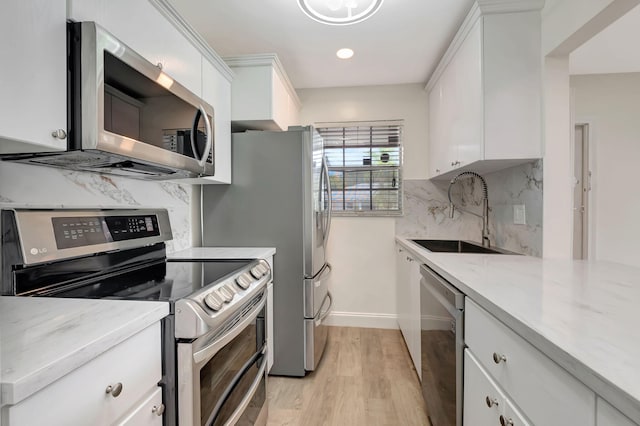 kitchen featuring tasteful backsplash, light hardwood / wood-style flooring, white cabinetry, and stainless steel appliances