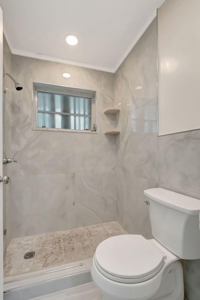 bathroom featuring tiled shower, crown molding, toilet, and tile walls