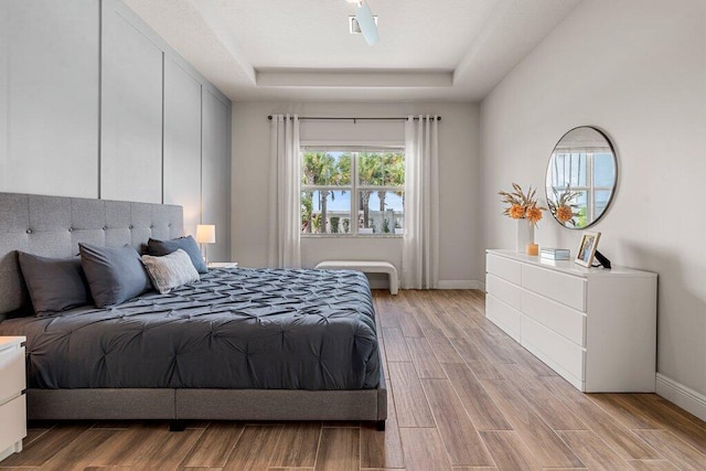 bedroom featuring light wood-type flooring and a tray ceiling