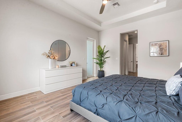 bedroom featuring a raised ceiling, ceiling fan, and light hardwood / wood-style floors