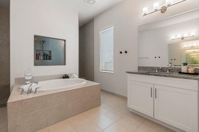 bathroom featuring tile patterned flooring, a relaxing tiled tub, and vanity