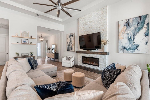 living room featuring ceiling fan, a stone fireplace, and wood-type flooring