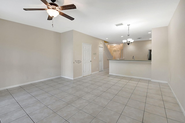 spare room with ceiling fan with notable chandelier and light tile patterned floors