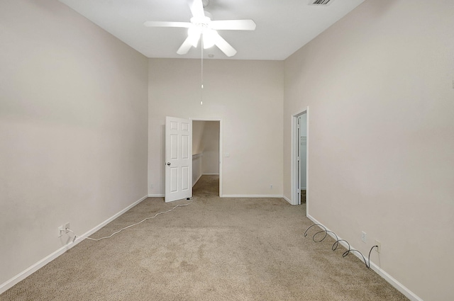 unfurnished bedroom featuring a towering ceiling, ceiling fan, and light colored carpet