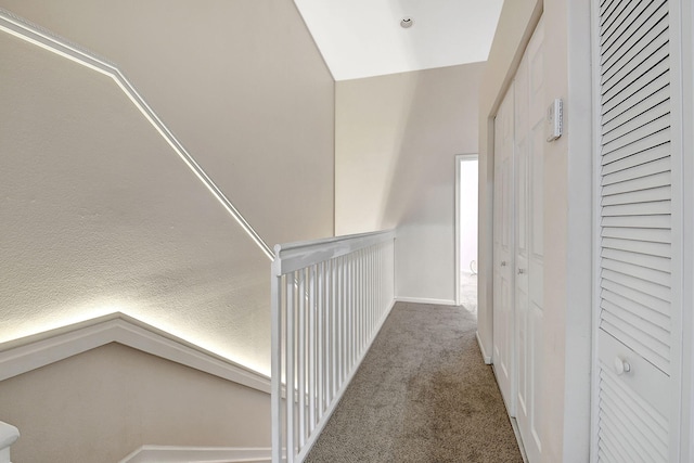 hallway featuring lofted ceiling, a textured ceiling, and carpet floors