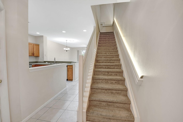 staircase with a notable chandelier and tile patterned floors