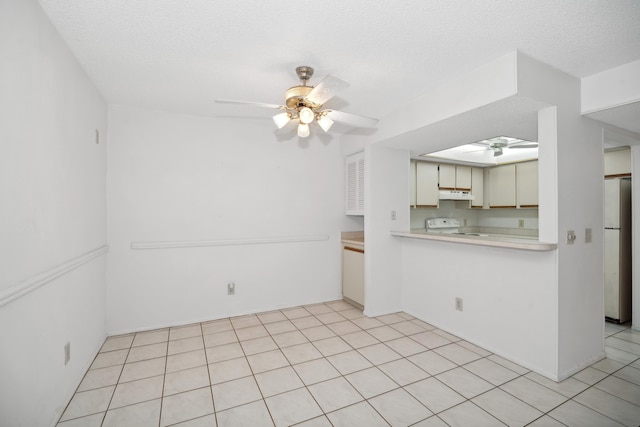 kitchen with a textured ceiling, white range, ceiling fan, light tile patterned floors, and fridge