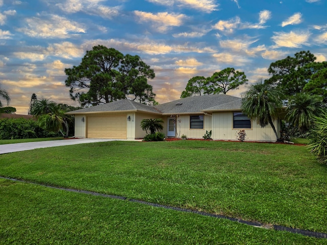 ranch-style house featuring a garage and a yard