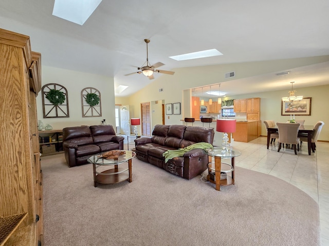 living room featuring vaulted ceiling with skylight, light tile patterned flooring, and ceiling fan with notable chandelier