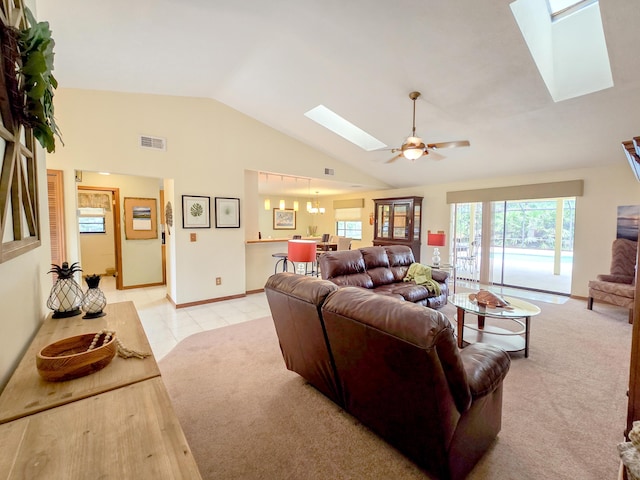 carpeted living room with vaulted ceiling with skylight and ceiling fan with notable chandelier