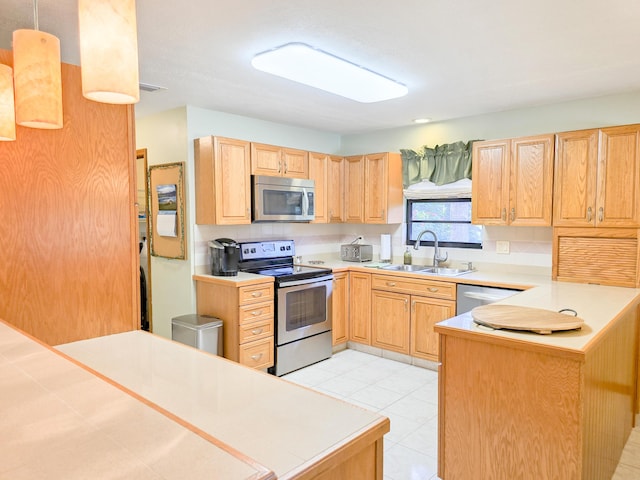 kitchen featuring kitchen peninsula, appliances with stainless steel finishes, light tile patterned floors, and sink