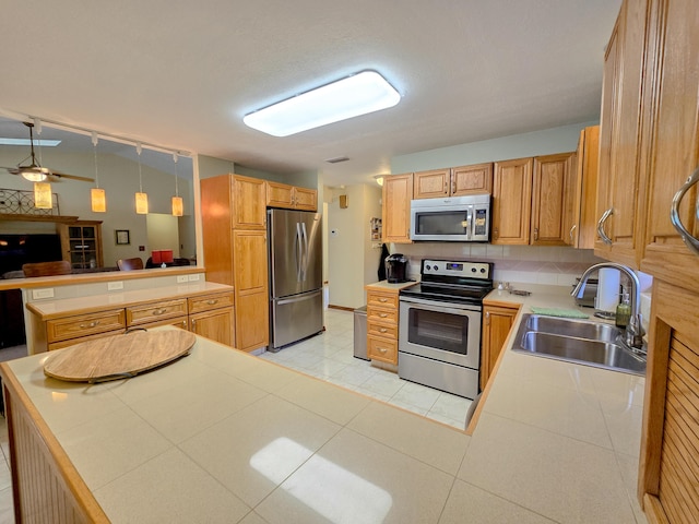 kitchen featuring sink, appliances with stainless steel finishes, decorative light fixtures, light tile patterned flooring, and kitchen peninsula