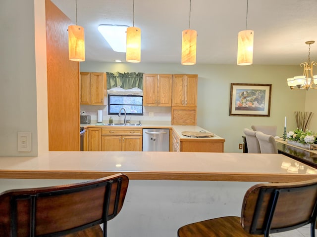 kitchen featuring sink, decorative light fixtures, dishwasher, a chandelier, and a breakfast bar area